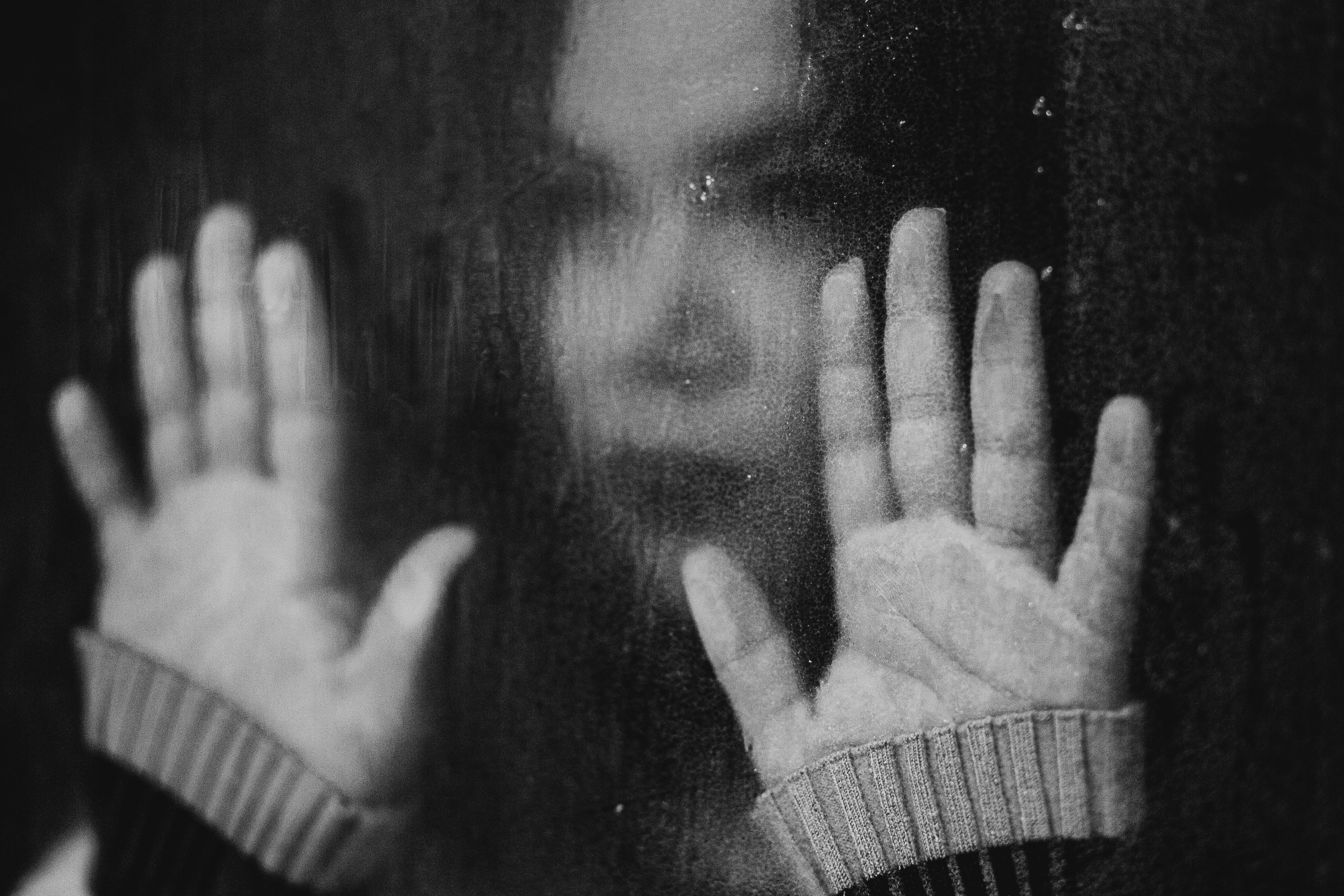 Person pressing hands against glass, a powerful image of isolation and fear at diagnosis